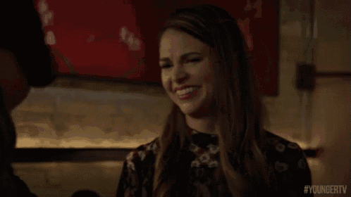 a woman is laughing while sitting at a table with a man .