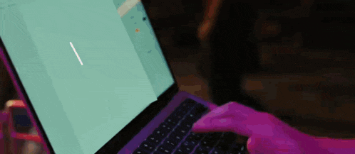 a person is typing on a purple laptop with a blue screen