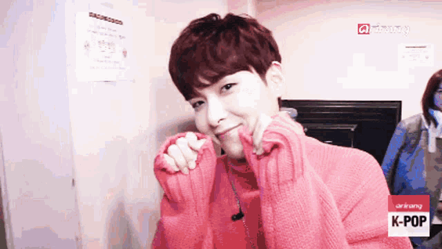 a young man wearing a pink sweater with k-pop written on it