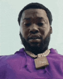 a man with a beard is wearing a purple hoodie and necklace .
