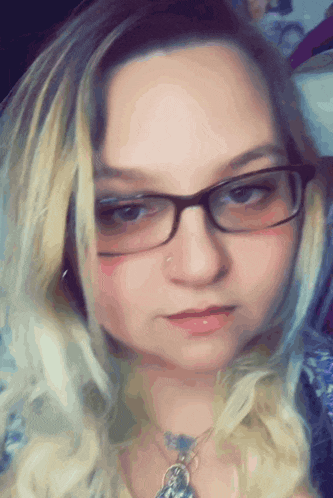 a woman wearing glasses and a necklace is making a face