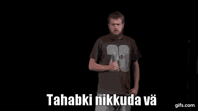 a man with a beard is standing on a stage holding a microphone and talking into it .