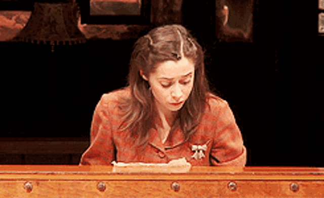 a woman is sitting at a desk with a piece of paper on it