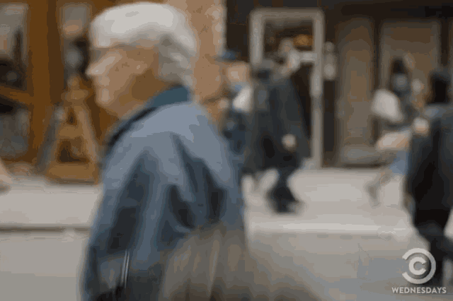 a blurry picture of people walking down a street with the words wednesdays on the bottom right