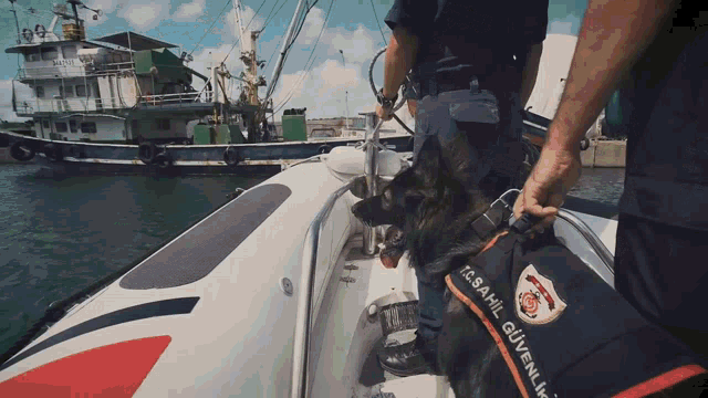 a man stands on a boat with a dog wearing a vest that says k.s.a.hil güvenlik