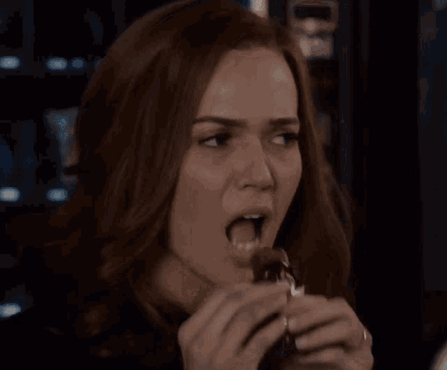 a close up of a woman eating a chocolate bar .
