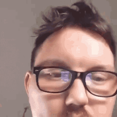 a close up of a man wearing glasses and making a funny face .
