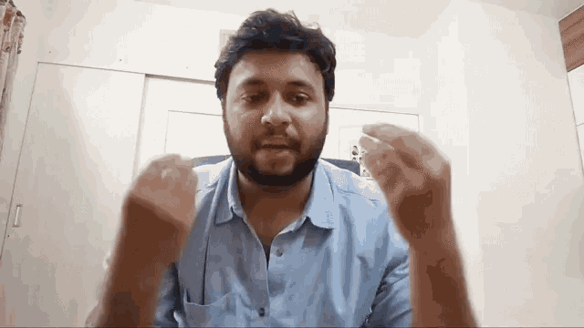 a man with a beard and a blue shirt is making a funny face .