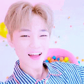 a young man is smiling in a ball pit filled with lots of colorful balls .