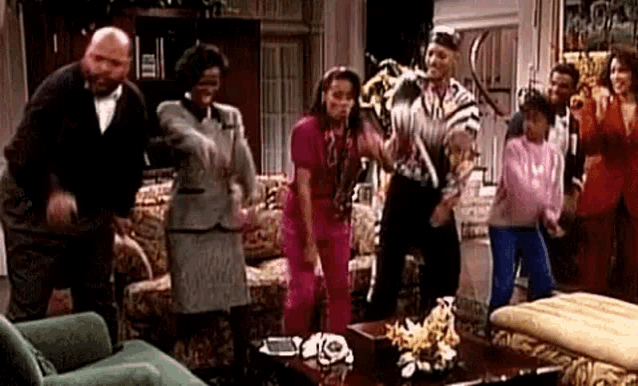 a group of people are standing in a living room dancing together .