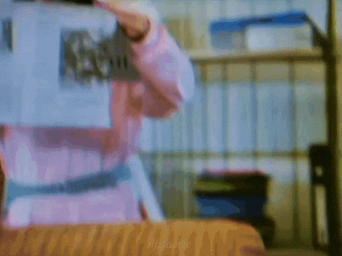 a woman in a pink dress is holding a piece of paper in her hands .