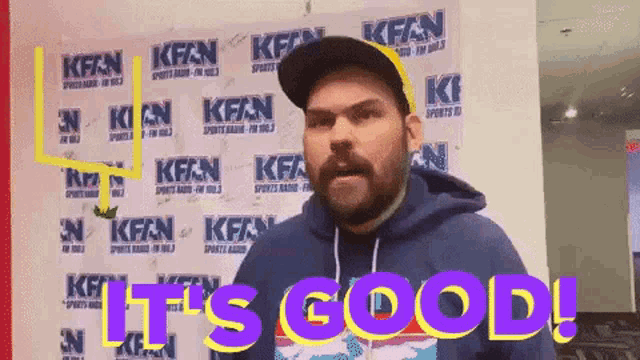 a man standing in front of a wall that says kfan on it