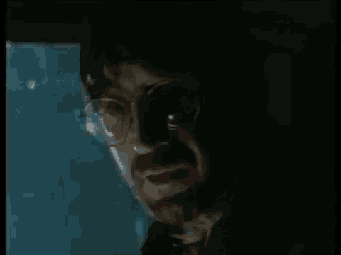 a close up of a man 's face in a dark room with a bloody neck .