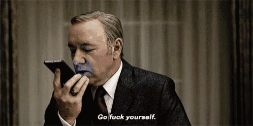 a man in a suit and tie is talking on a cell phone with a blue face painted on his face .