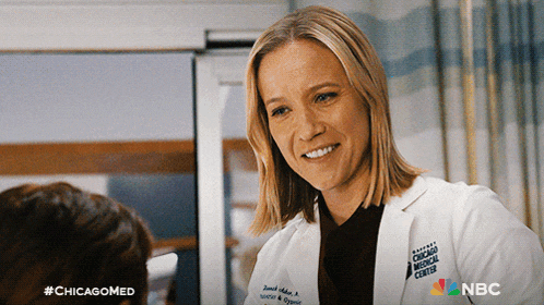 a woman in a chicago medical center lab coat smiles while talking to a patient