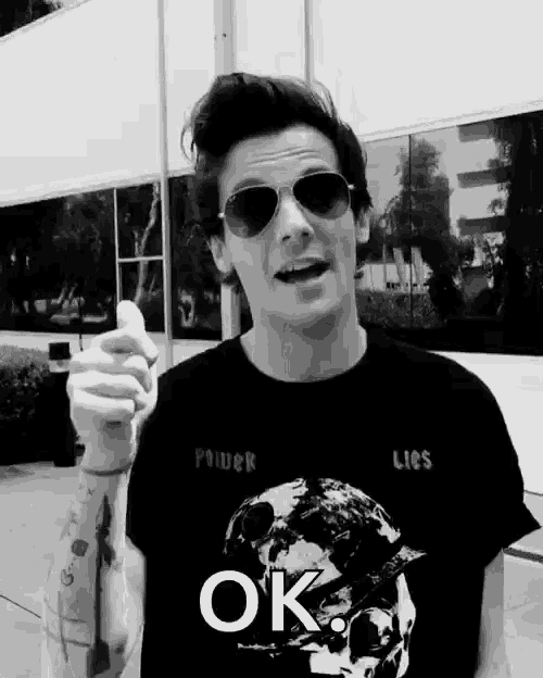 a black and white photo of a man wearing sunglasses and a t-shirt that says power lies ok