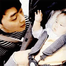 a man is kissing a baby in a car seat