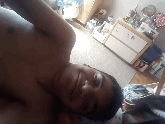 a shirtless man is laying on a bed in a room