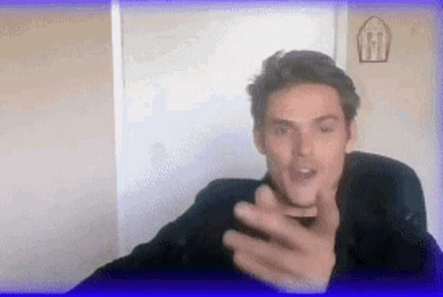 a man in a black shirt is making a funny face while talking on a video call