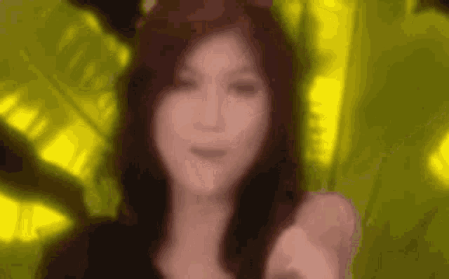 a blurry picture of a woman pointing at the camera in front of a yellow background .