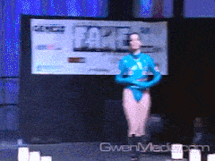 a woman in a blue leotard stands in front of a screen that says fake