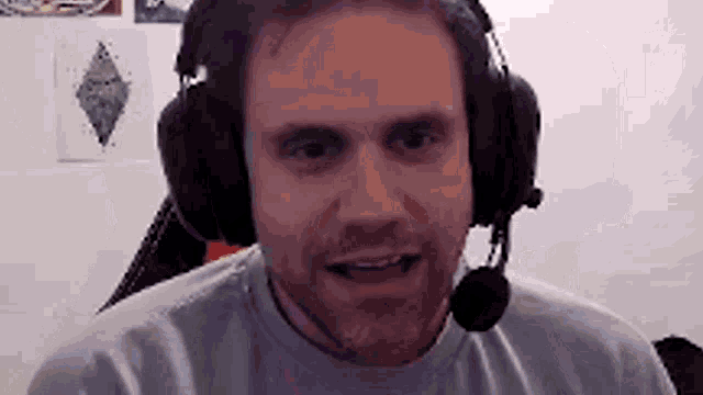 a man with a beard is wearing headphones and a microphone while sitting in a chair .