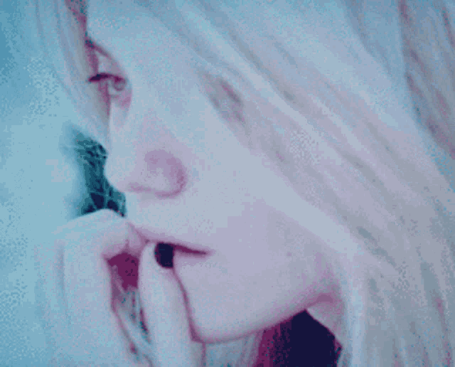 a close up of a woman 's face with her hand on her lips
