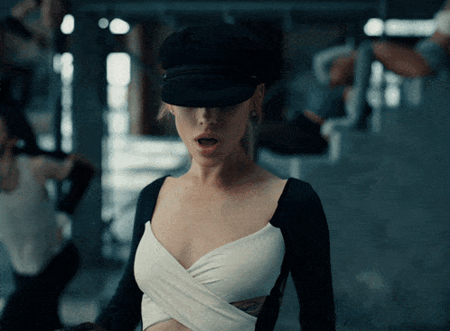 a woman wearing a black hat and a white top has a tattoo on her arm