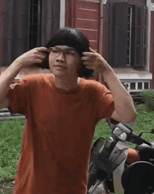 a man with short hair and glasses is running in front of a motorcycle .