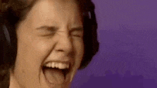 a woman wearing headphones is screaming with her mouth open and her eyes closed .