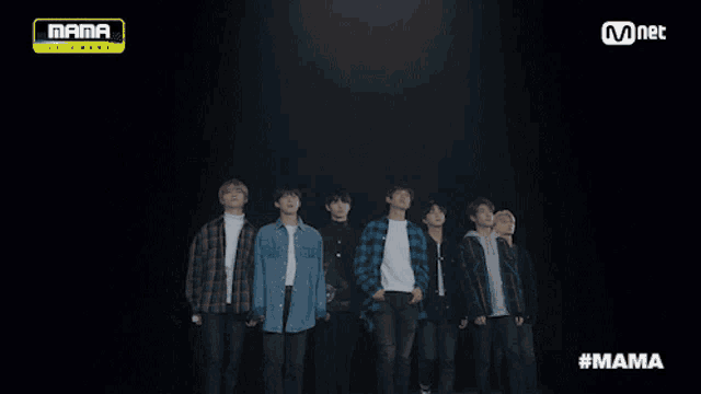 a group of young men standing next to each other in front of a mnet banner