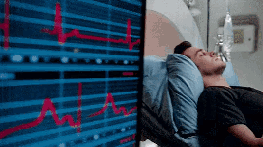 a man is laying in a hospital bed looking at a monitor