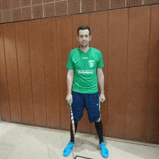 a man in a green shirt and blue shorts holds a racket