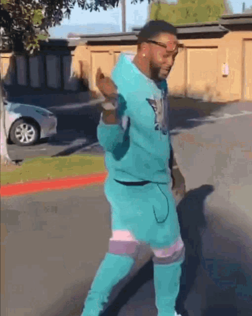 a man in a blue hoodie and pants is dancing on the street