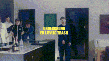 a group of people are standing in a room with the words undergrunn er jevlig trash written in yellow