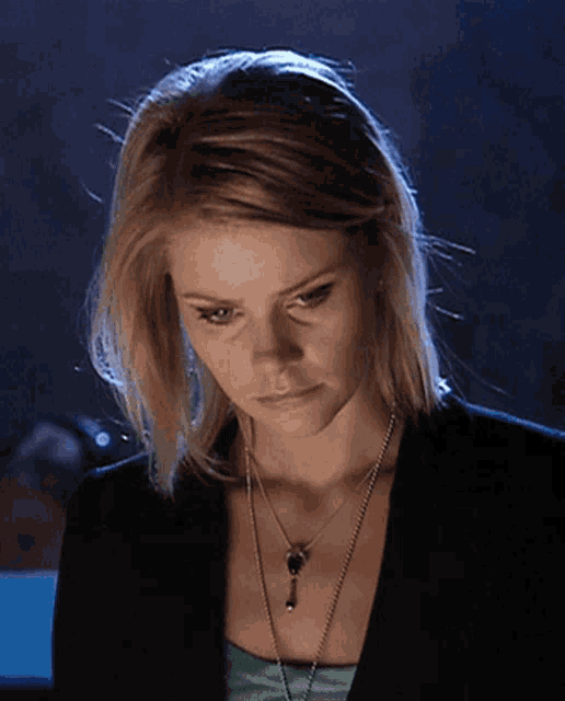 a woman wearing a black jacket and a necklace with a key on it