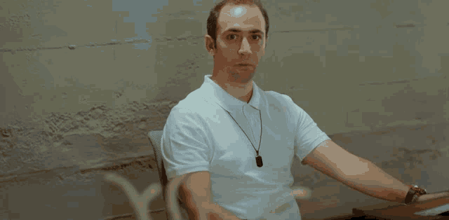 a man wearing a white polo shirt with a necklace around his neck
