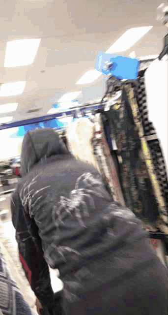 a person in a black hoodie is standing in a store