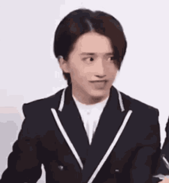 a young man in a black suit and white shirt is making a funny face .