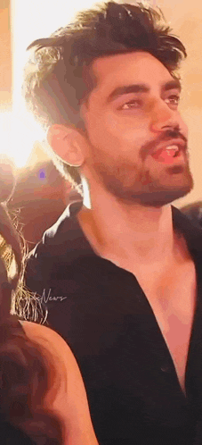 a close up of a man with a beard wearing a black shirt with his tongue hanging out .