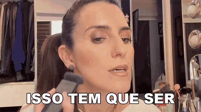 a woman applying makeup with the words isso tem que ser written on her face