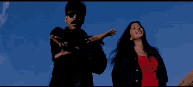 a man and woman are standing in front of a blue sky