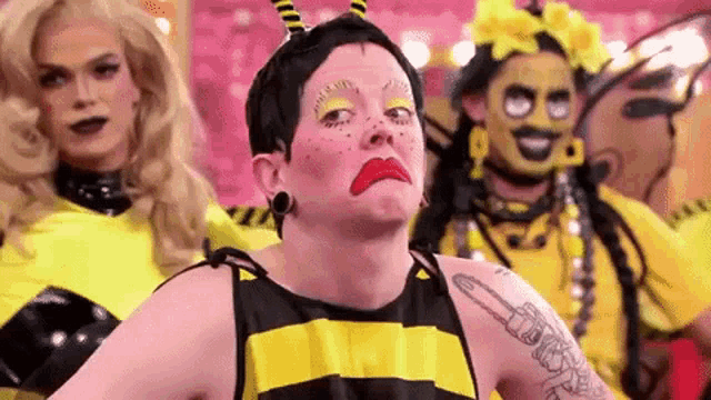 a woman in a bee costume is making a funny face while standing next to two other women in bee costumes .