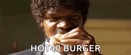 a man with curly hair is eating a hot 40 burger .