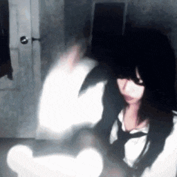 a woman with long black hair is sitting in a dark room with a light behind her