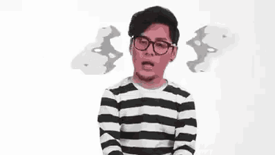 a man wearing glasses and a striped shirt is making a funny face in a video .