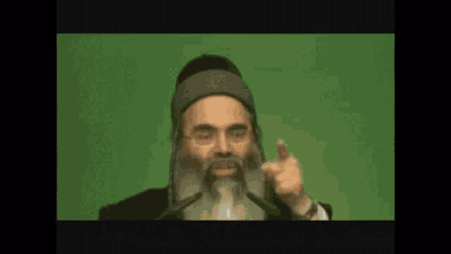 a man with a beard and glasses is giving a speech in front of a green background .