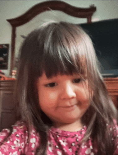 a little girl wearing a pink shirt with flowers on it