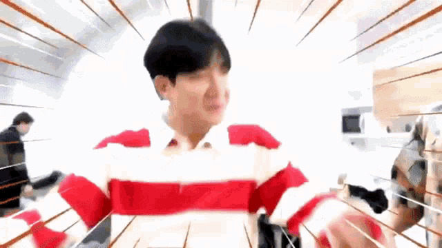 a man in a red and white striped shirt is standing in front of a microwave