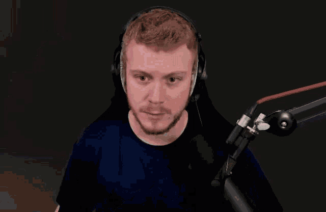 a man wearing headphones is sitting in front of a microphone .